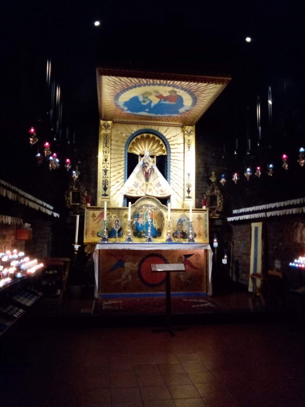 Inside of the Holy House at Walsingham - there is a statue of Our Lady of Walsingham above an altar and there are candles and that around.